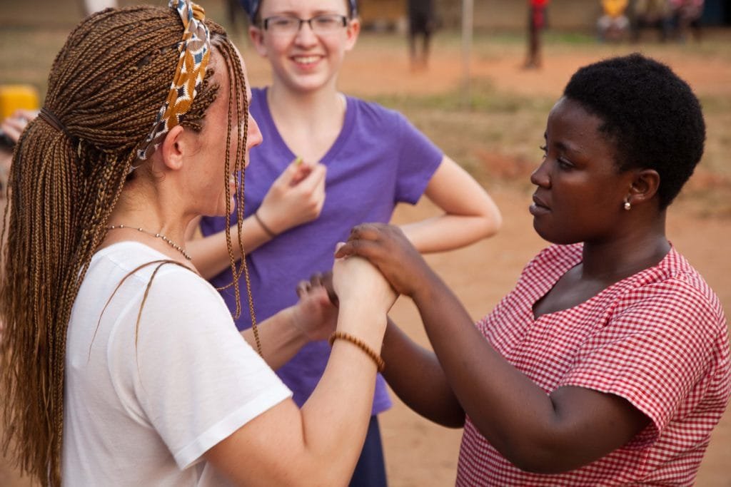 A woman is watching 2 other women holding hands