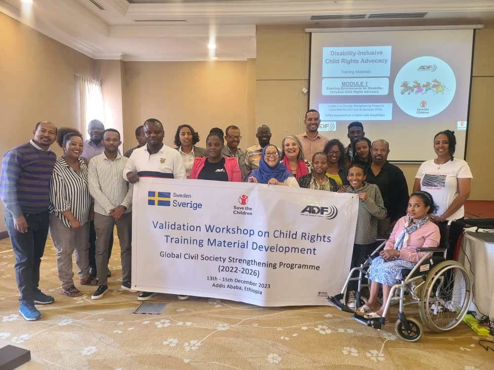 a group of people standing together with a banner that says: validation workshop on child rights training material development. Global civil society strengthening programme (2022-2026)