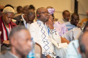 The camera is focused on one man at the conference listening to the panellists with language translation headphones on his head