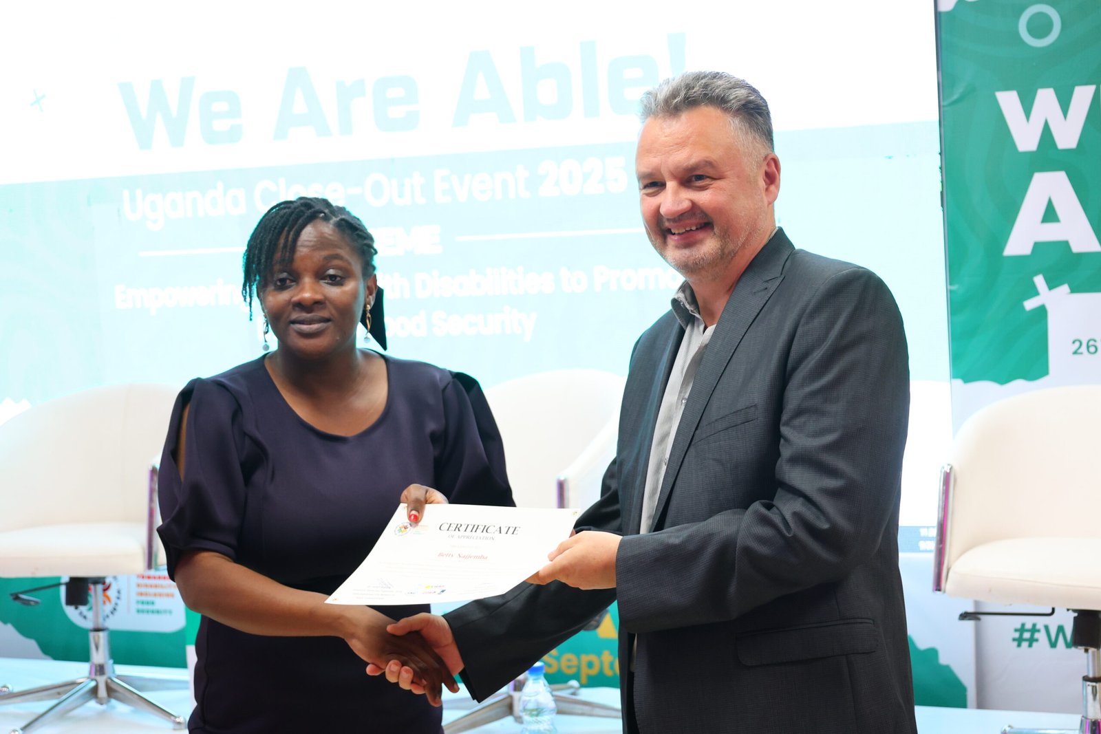 ADF Project Officer, Betty Najjemba is handed a certificate by Consortium Coordinator We are Able!, Bob van Dillen