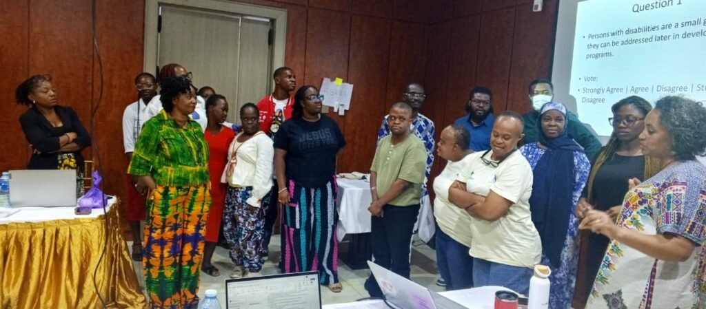 A diverse group of people stand in a conference room, engaging with a presentation during the mission in Abuja, Nigeria.