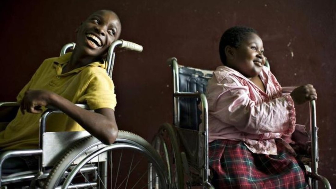 A boy and a girl both in wheelchairs looking on the right and smiling||Survey Image