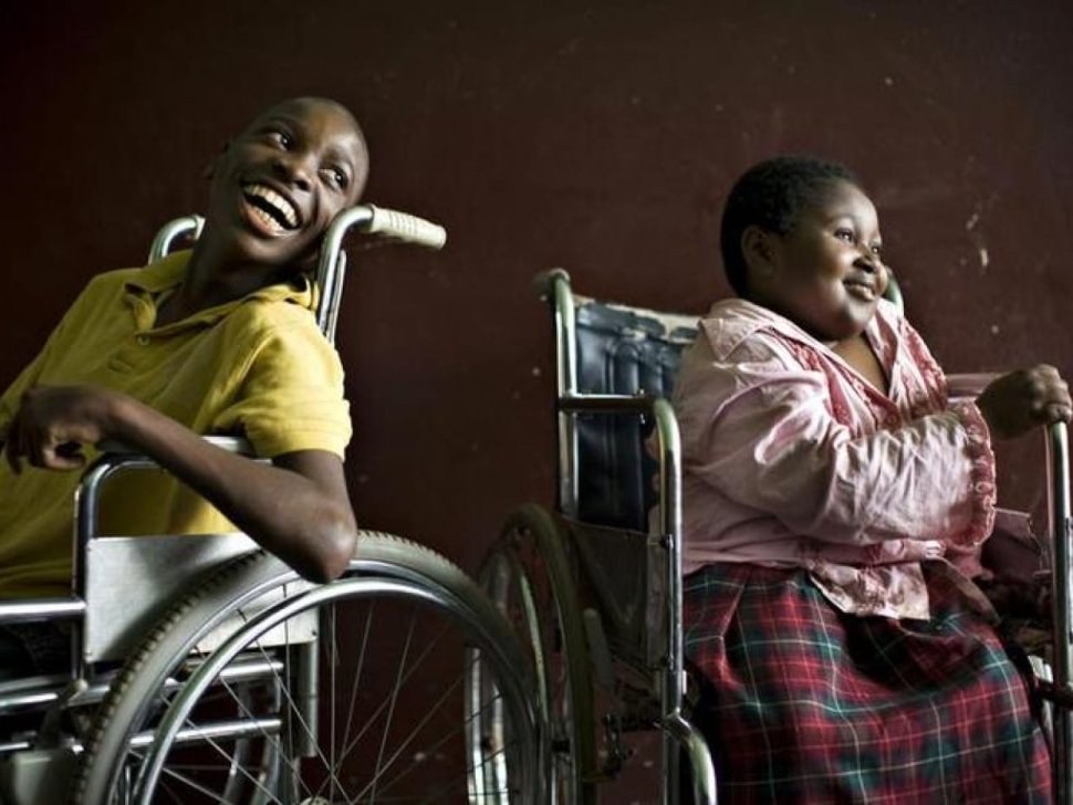 A boy and a girl both in wheelchairs looking on the right and smiling||Survey Image