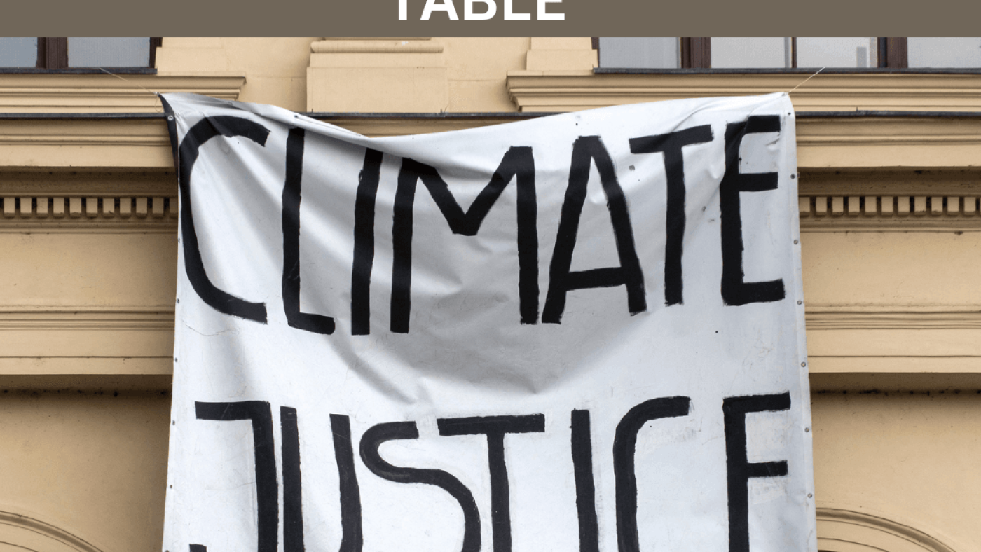 Heading that reads: Global disability movement demands seat at the “COP table”, underneath a picture shows a banner hanging that reads: Climate Justice