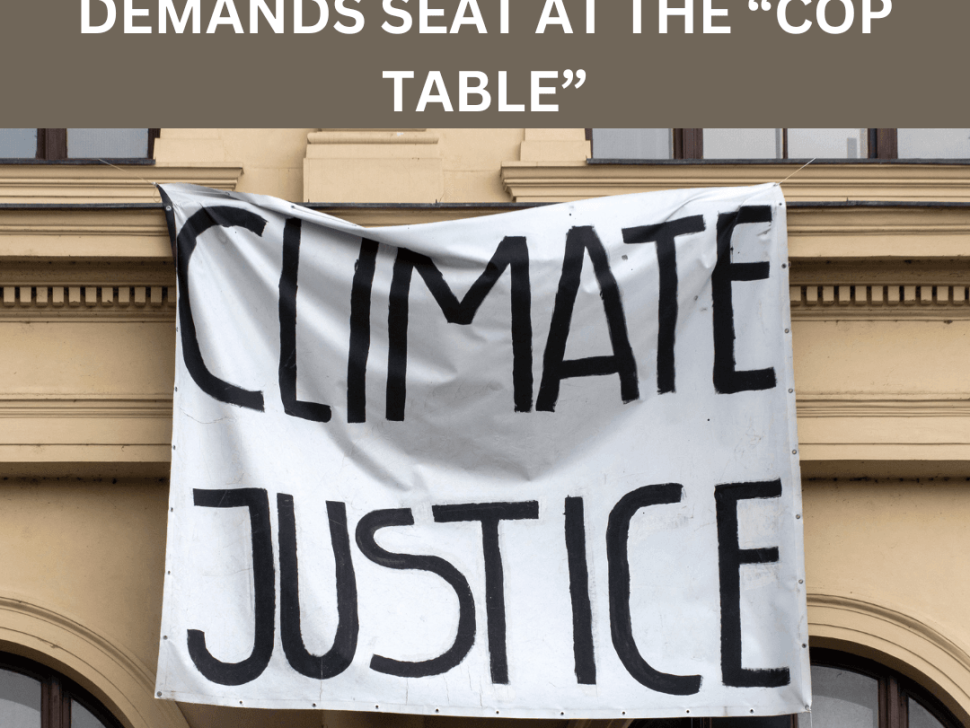Heading that reads: Global disability movement demands seat at the “COP table”, underneath a picture shows a banner hanging that reads: Climate Justice